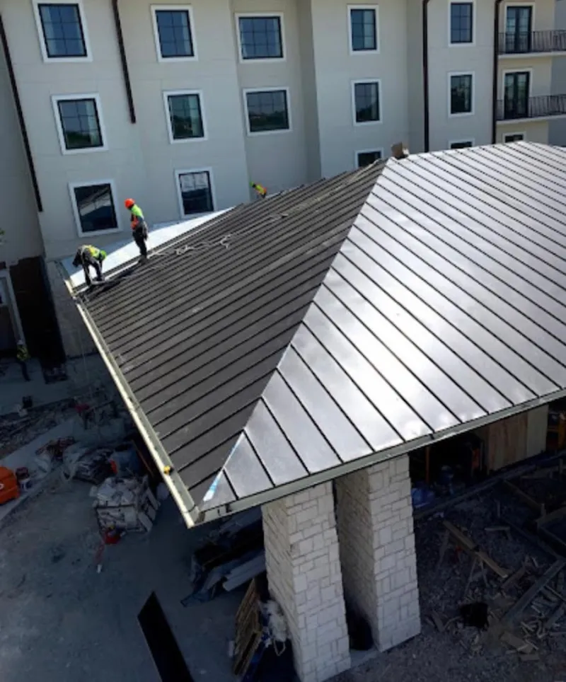 Crew installing standing seam metal roof panels on a commercial project in Liberty Triangle